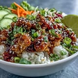 Ground turkey coated in creamy bang bang sauce over rice with crunchy carrots, cucumbers, and red cabbage for a colorful bowl.