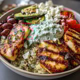 Sliced halloumi and smoky zucchini mingle over quinoa in this Healthy Grilled Mediterranean Bowl, drizzled with creamy tzatziki sauce.