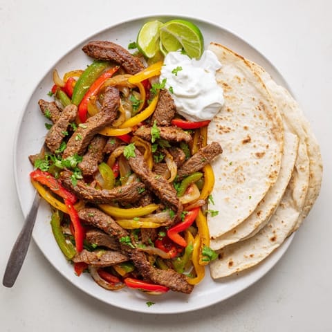 Colorful Steak Fajitas sizzling in a skillet, topped with fresh cilantro and creamy avocado slices.