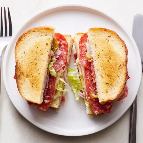 Golden-brown Italian Sub Grilled Cheese sandwich on a plate, melted provolone and salami peeking from crispy grilled bread.  
