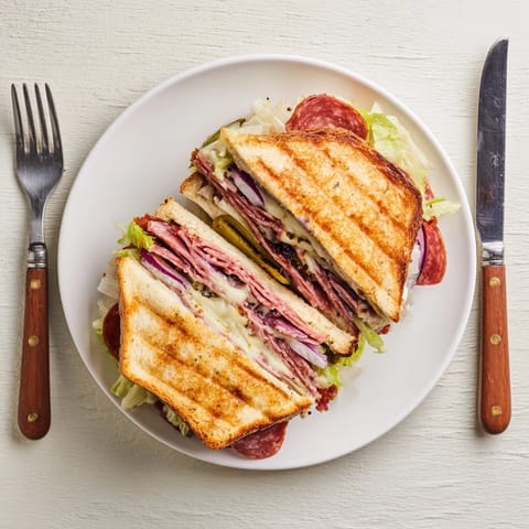A close-up of Italian Sub Grilled Cheese, showing layered salami, pepperoni, and tangy lettuce topping between buttery slices.  