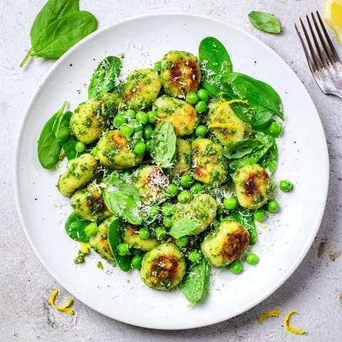 Crispy golden gnocchi with sweet green peas tossed in bright basil pesto in a skillet.