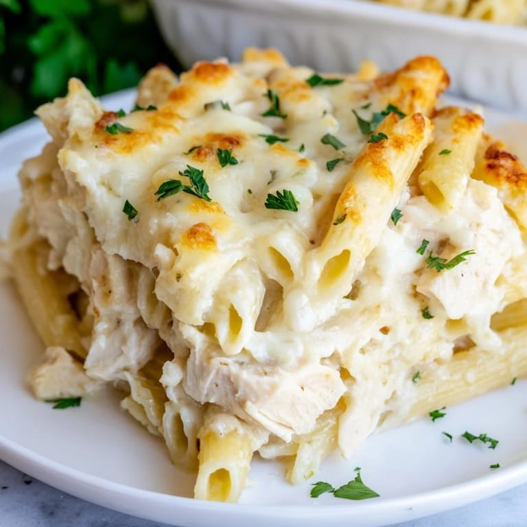 A bubbling Chicken Alfredo Bake casserole served alongside a crisp green salad.