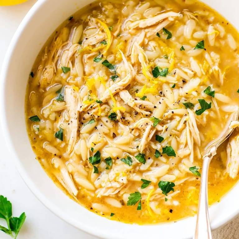 Close-up of Lemon Pepper Chicken Orzo Soup featuring zesty lemon wedges and aromatic black pepper.  