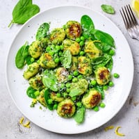 Crispy golden gnocchi with sweet green peas tossed in bright basil pesto in a skillet.