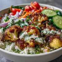 Roasted Cauliflower Bowl with golden herb-roasted cauliflower, fluffy rice, and vibrant veggies drizzled in creamy tahini sauce.