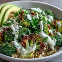 Golden roasted broccoli and red onion slices rest atop fluffy quinoa in this Roasted Broccoli Bowl, drizzled with creamy tahini sauce and sprinkled with fresh parsley.  