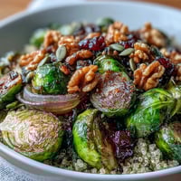 Golden roasted Brussels sprouts and red onions top a bed of fluffy quinoa in this vibrant vegetarian bowl, drizzled with tangy balsamic dressing.