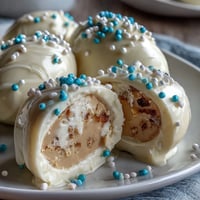 Festive white chocolate peanut butter Easter eggs decorated with colorful sprinkles on a pastel plate.